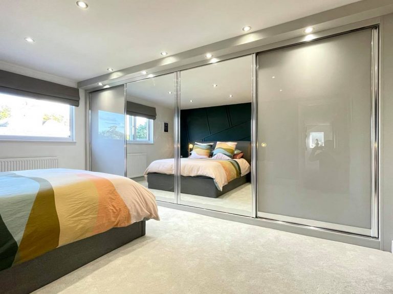 Light Grey & Mirror Sliding Wardrobes With Built in TV Unit by James Kilner in Wakefield